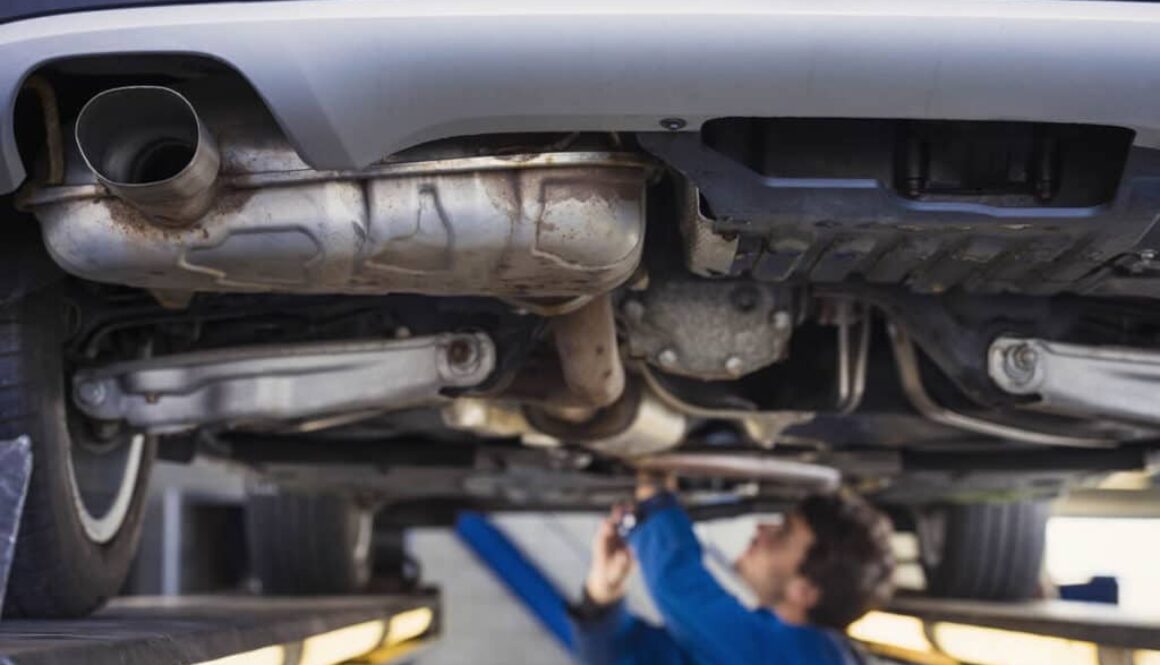 Exhaust of a car with mechanic underneath